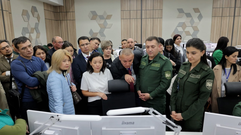 Employees of the State Customs Service of Turkmenistan stand in front of several screens at the NTFC meeting in Uzbekistan.